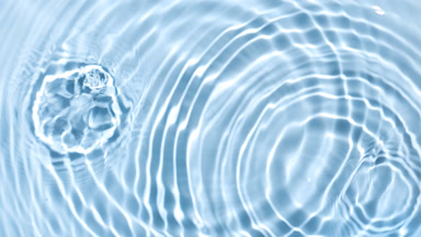Multiple drops falling in water on blue background