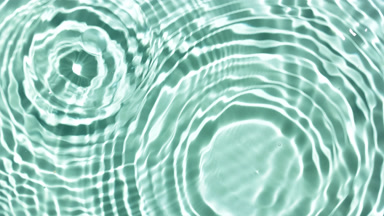 Multiple water drops falling on water surface on green bg