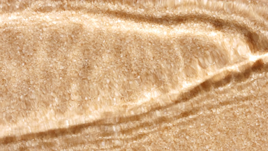 Water waves crossing and splashing on brown sugar crystals
