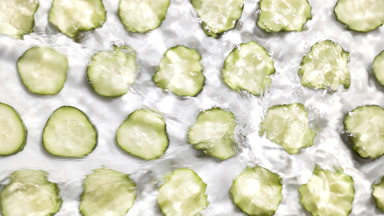 Poured water makes splashes and ripples over cucumber slices