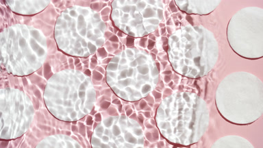 Single wave of water creates ripples on cotton pad background
