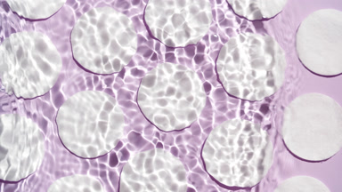 Wave makes water ripples over cotton pads on purple