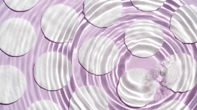 Drops falling in water making circles over cotton pads on purple