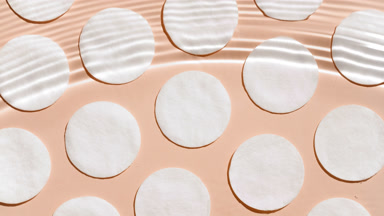 Wave splashing and making ripples over cotton pads on beige bg