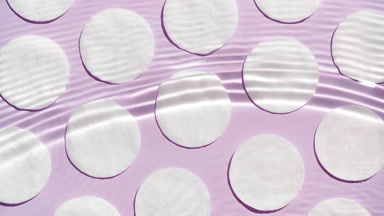 Wave splashing and making ripples over cotton pads on purple