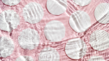 Waves cross each other creating ripples on pale pink background