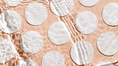 Waves crossing and splashing against cotton pads on beige bg