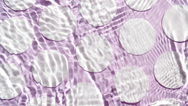 Waves crossing and splashing against cotton pads on purple bg