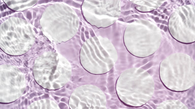 Water ripples and waves over cotton pads on purple bg
