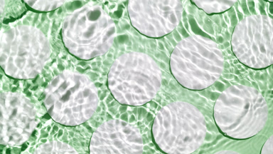 Water splashes and makes ripples over cotton pads on green bg