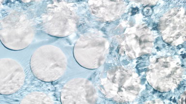 Poured water makes splashes and ripples over cotton pads on blue