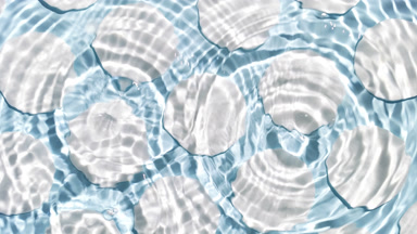 Drops falling in water making circles over cotton pads on blue