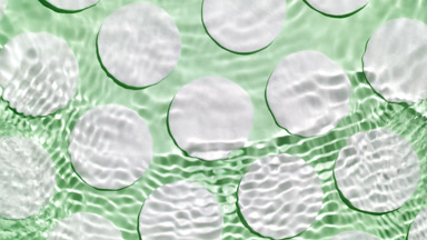 Water waves crossing and splashing against cotton pads on green