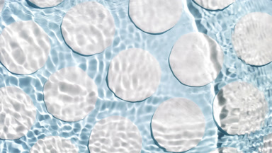 Water waves crossing and splashing against cotton pads on blue