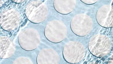 Water waves and ripples crossing against cotton pads on blue bg
