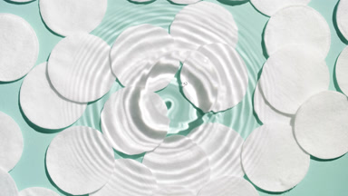 Drop falls down on water creating rings on green background