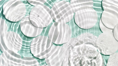Falling drops making water rings over cotton pads on green bg