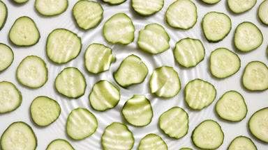 Drop makes ripples on water surface over cucumber slices