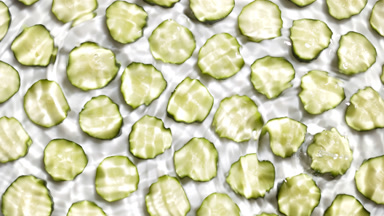 Drops are falling in water making circles over cucumber slices