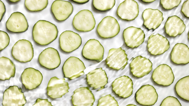 Wave of water creates ripples over cucumber slices