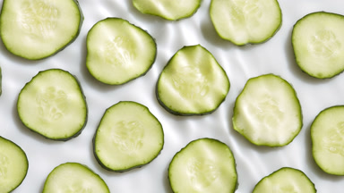 Wave makes ripples on water surface over sliced cucumber