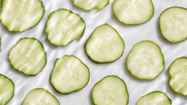 water waves and ripples crossing over cucumber slices on white