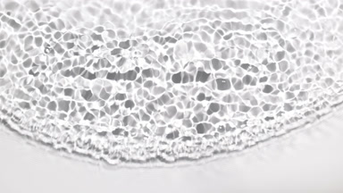 Single wave of clear liquid ripples on pale grey background