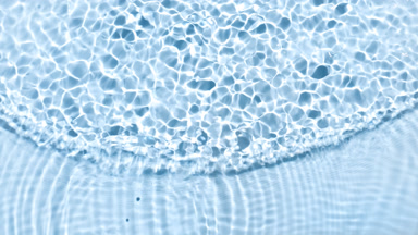 Drops falling in water with wave on blue bg