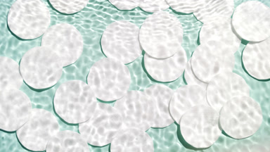 Wave splashing on water surface over cotton pads on green bg