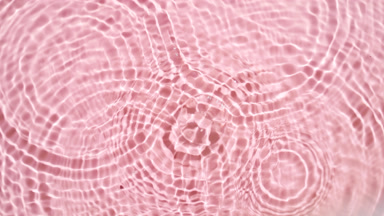 Drops falling in water making multiple water rings on pink bg