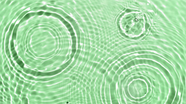 A lot of clear drops fall down on water surface creating circles