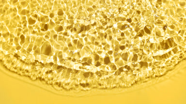 Wave makes ripples and splashes on water surface on yellow bg