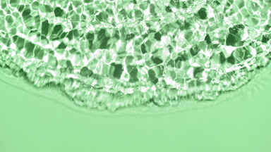 Wave makes ripples and splashes on water surface on green bg