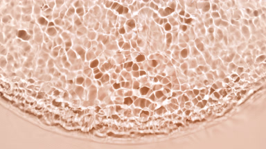 Wave of clear liquid ripples spontaneously on beige background
