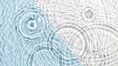 Drops falling in water making multiple rings on blue and white