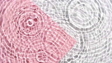 Drops falling in water making circles on pink and white bg