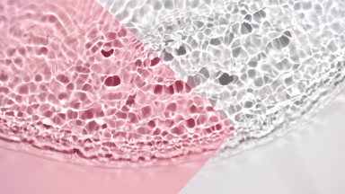 Wave makes ripples on water surface over pink and white bg