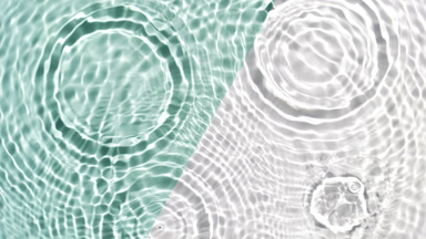 Clear drops fall down creating rings on rippling water surface
