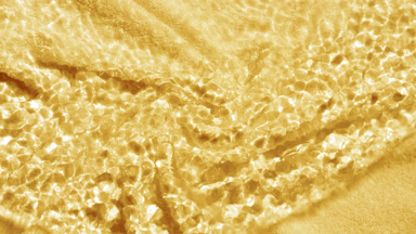 Wave makes ripples on water surface over yellow terry towel bg