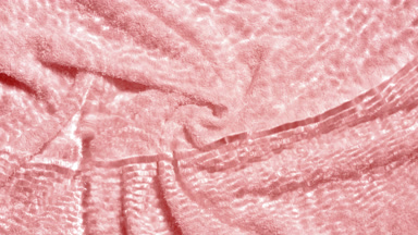 Wave makes ripples on water surface over pink terry towel bg