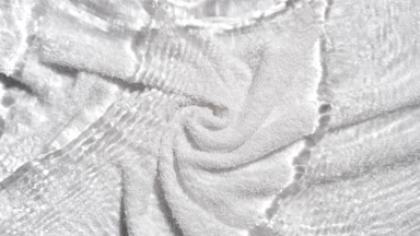 Water waves crossing and splashing over white terry towel bg