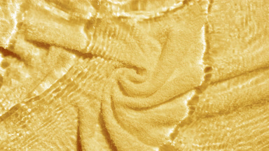 Multiple waves cross each other creating ripples on yellow towel
