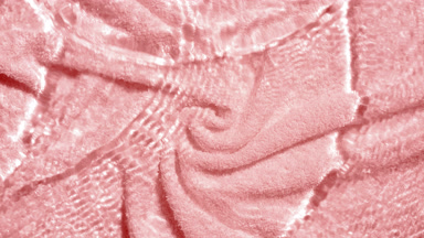 Water waves crossing and splashing over pink terry towel bg