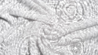 Drops falling in water making rings over white terry towel bg