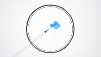 Dropper injects blue liquid into transparent one in Petri dish