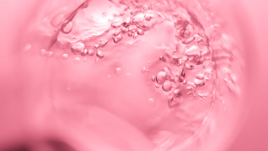 Transparent liquid pouring into beaker creates bursting bubbles