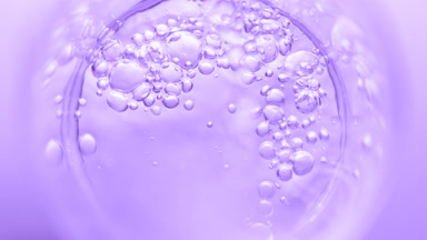 Transparent liquid pouring into beaker creates bursting bubbles