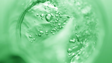 Transparent liquid pouring into beaker creates bursting bubbles