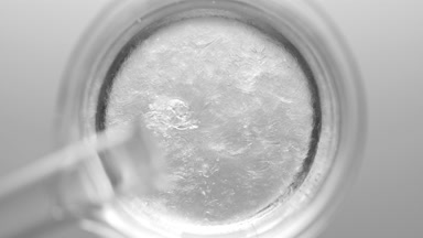 Glycerin pouring into beaker with water creates ripples