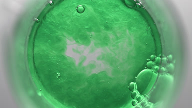 Green liquid pouring into beaker with water and glycerin